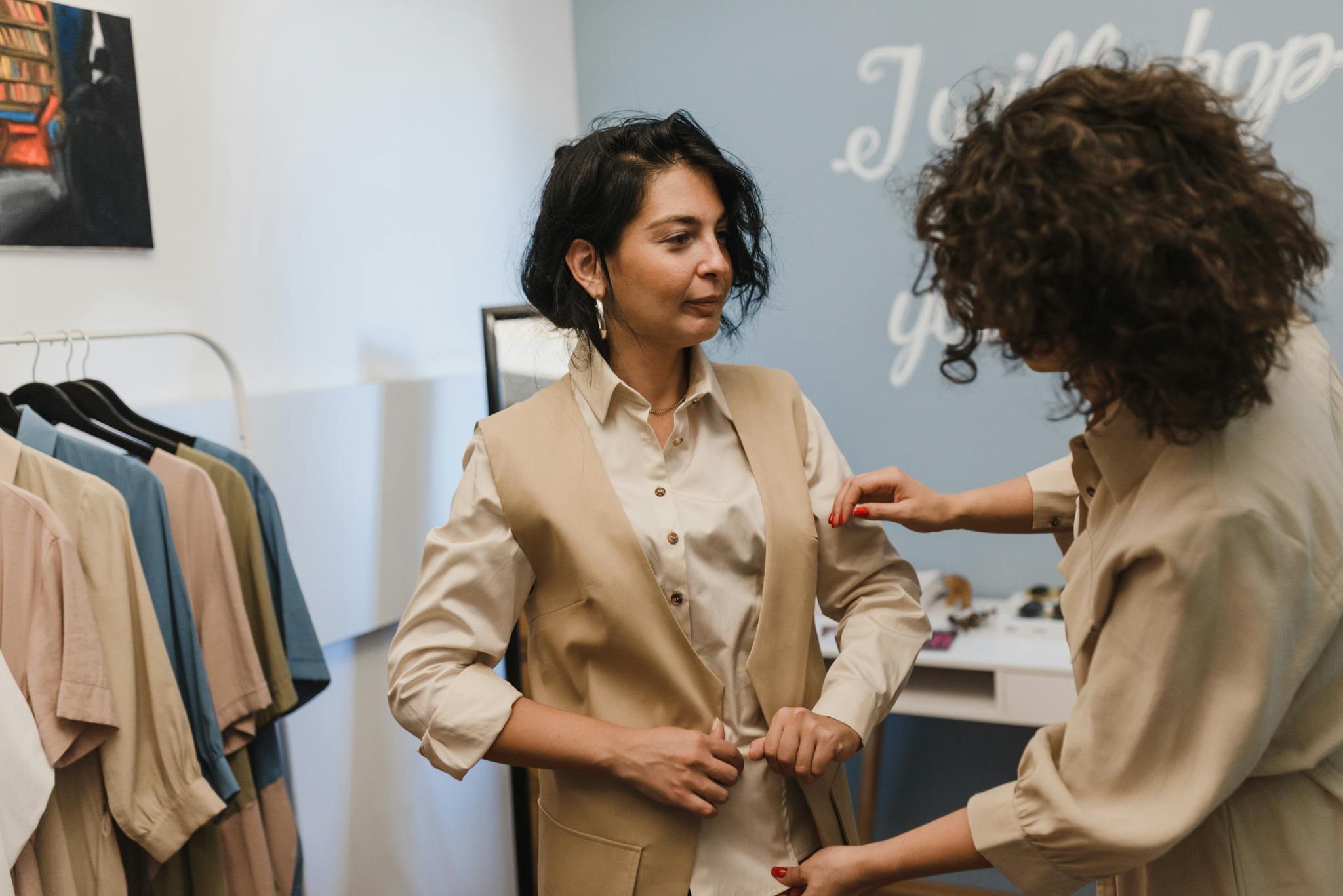 A fashion stylist helps a woman adjust her outfit in a trendy boutique.